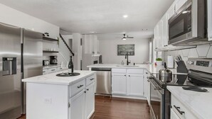 A modern kitchen with white cabinetry, stainless steel appliances, and a central island. - Contemporary home in the heart of McKinney (McKinney)