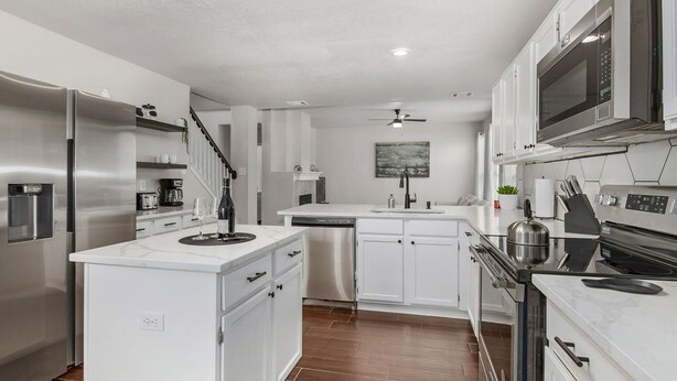 A modern kitchen with white cabinetry, stainless steel appliances, and a central island. - Contemporary home in the heart of McKinney (McKinney)