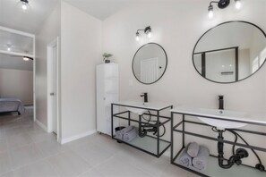 A modern bathroom with a double sink, a large mirror, and a towel rack.