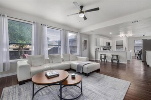 A modern living room with a sectional sofa, a coffee table, and a dining area with bar stools.