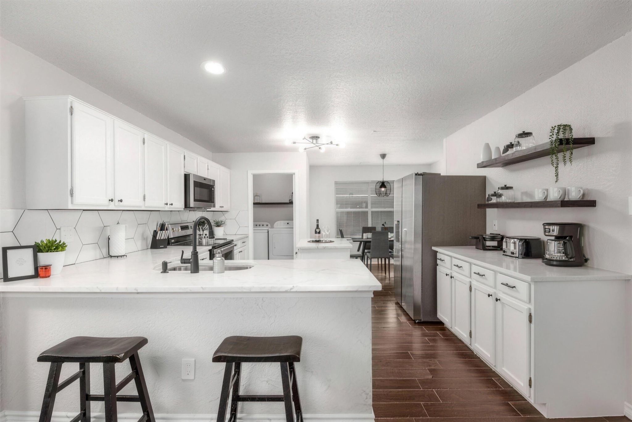 A modern kitchen with white cabinetry, a central island, and bar stools.