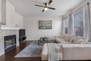 A living room with a fireplace, a sofa, a coffee table, and a painting on the wall.
