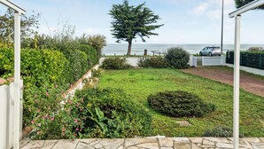 Un jardin avec une pelouse, un arbre et un chemin menant à une porte.