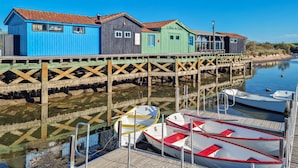 Une jetée bordée de bâtiments en bois aux couleurs vives et où sont amarrés des bateaux à son extrémité.