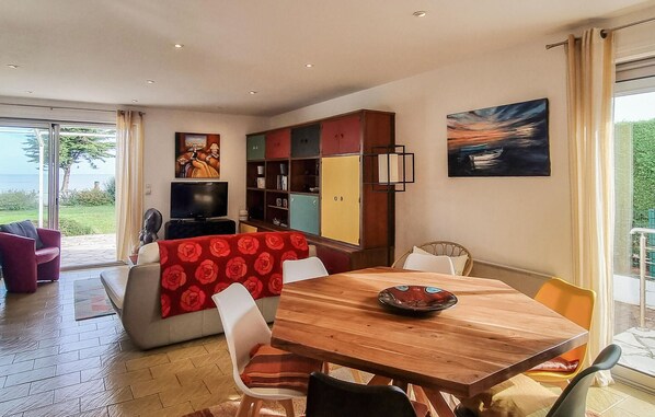 Un comedor con una mesa y sillas de madera, un televisor y una estantería.