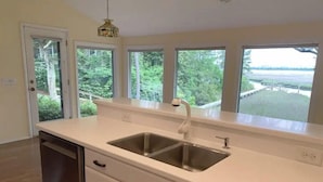 A kitchen with a large window, a dishwasher, and a sink. - MCM Magic on the Marsh (Mount Pleasant)