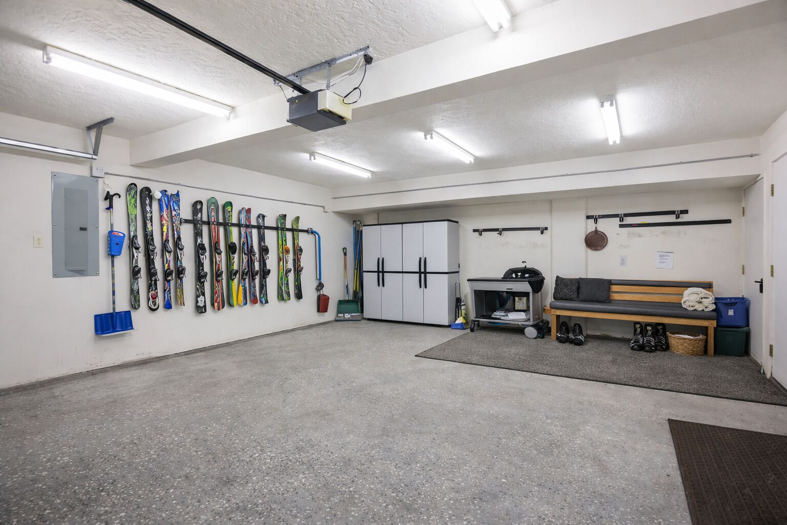 A ski storage room with skis, a bench, and a cart.