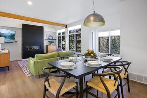 Uma sala de jantar com uma mesa posta para quatro pessoas, rodeada por cadeiras com assentos de fibra.