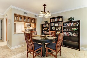 Uma sala de jantar com uma mesa redonda, quatro cadeiras e um candelabro.