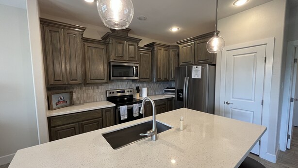 A modern kitchen with wooden cabinets, stainless steel appliances, and a large island with a sink. - Feet in the Sand Home- 13 Val (Laguna Vista)