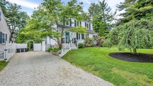 A two-story house with a front porch, a gravel driveway, and a well-maintained lawn.