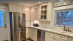 A modern kitchen with stainless steel appliances, white cabinetry, and a built-in dishwasher.