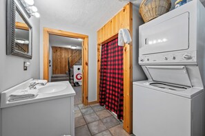 A bathroom with a white sink, mirror, and a white washing machine.