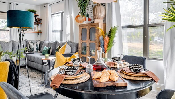 A dining area with a round table set for a meal, surrounded by modern furniture and decor.