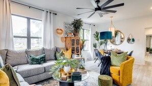 A modern living room with a grey sofa, yellow armchair, and a glass coffee table.