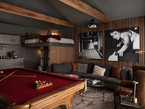 Una sala de estar acogedora con mesa de billar, un sofá y una cama litera.