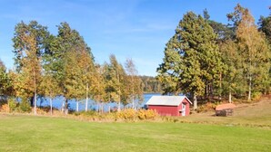 Eine rote Holzhütte an einem See, umgeben von Bäumen.