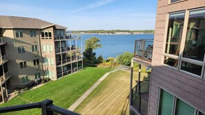 Una vista di un edificio residenziale con un prato e un corpo d'acqua sullo sfondo.
