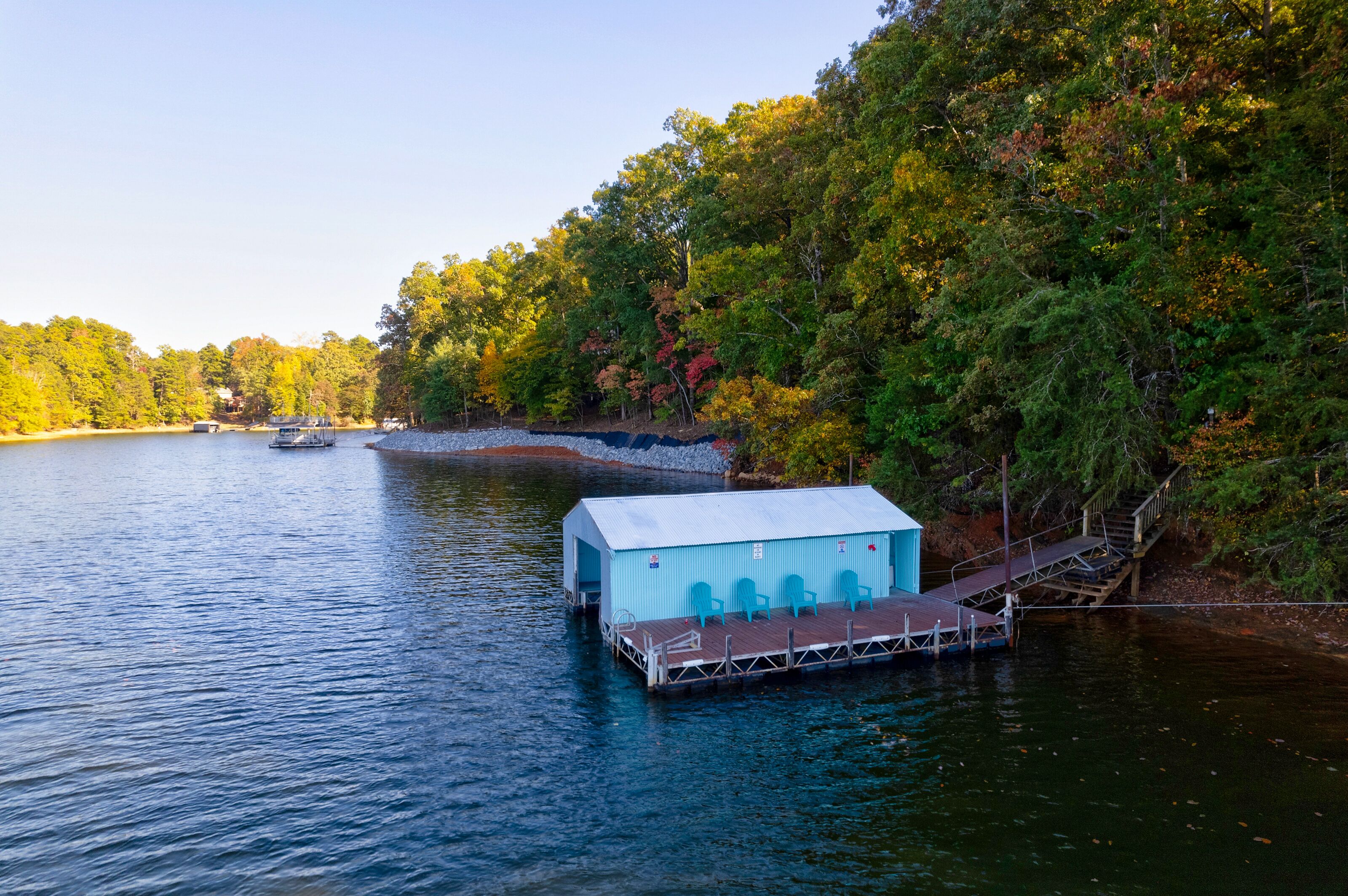 A dock with a blue building, a wooden walkway, and a boat in the background.