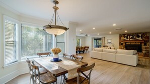A spacious living area with a dining table, chairs, a sofa, and a fireplace. - Lake Front Mountain View w/ 6 King beds (Gainesville)