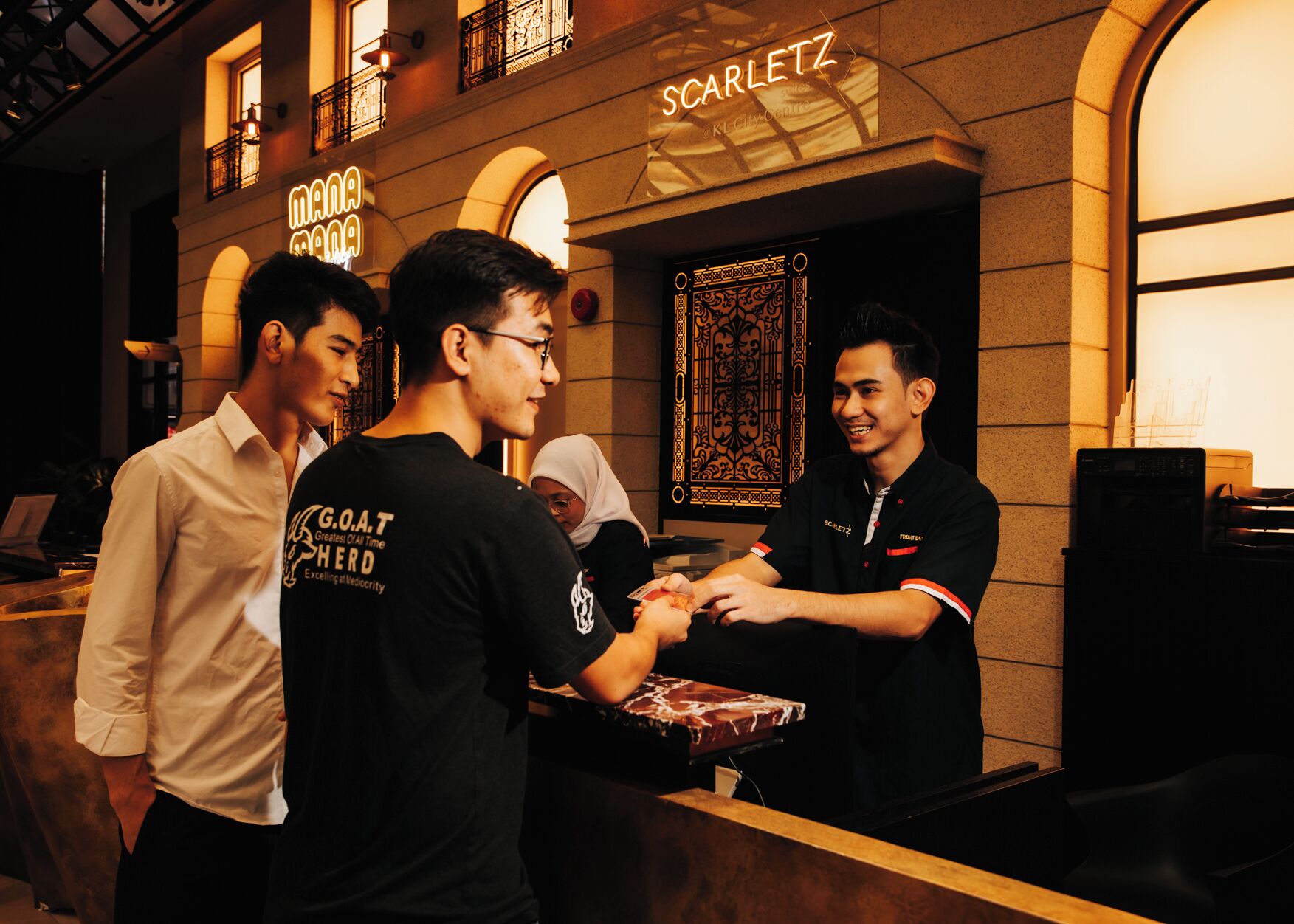 A group of people at a counter with a neon sign reading "Scarlett" above.