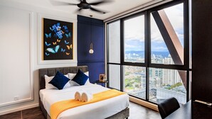 Ein modernes Hotelzimmer mit einem großen Bett, Blick auf die Stadt und einem Deckenventilator.