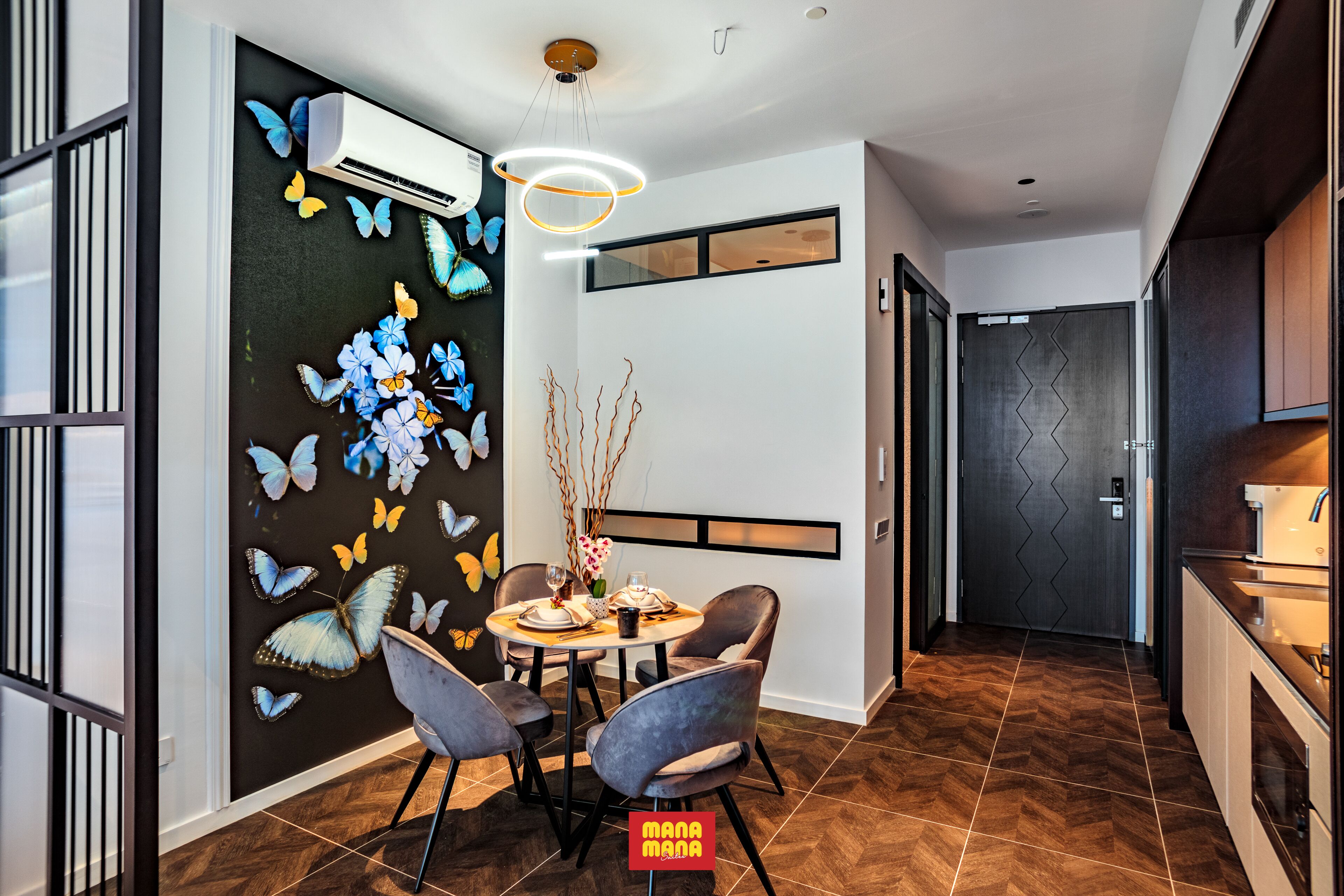 A modern dining area with a round table, chairs, and a decorative wall with butterfly motifs.