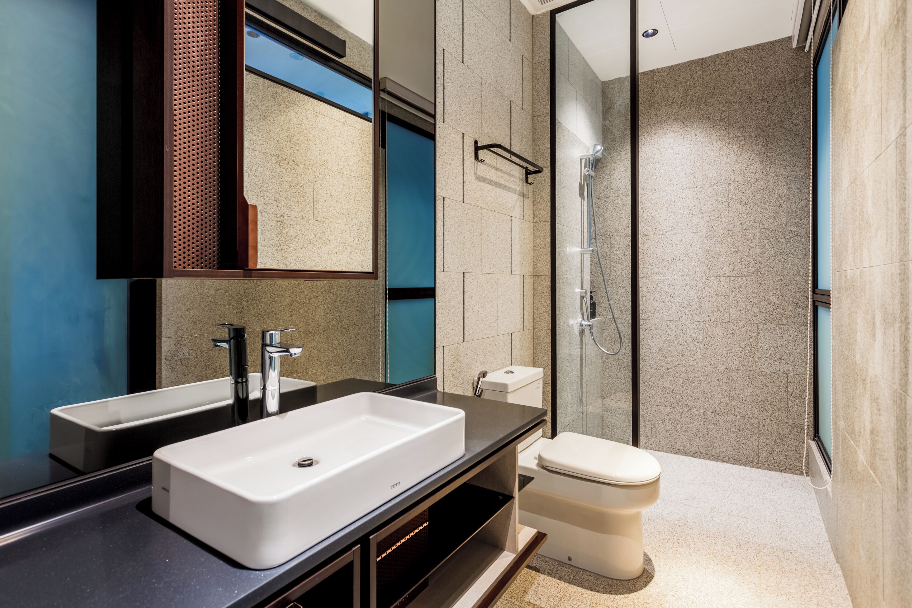 Un baño moderno con un espejo grande, dos lavamanos, un inodoro y una ducha con cerramiento de vidrio.