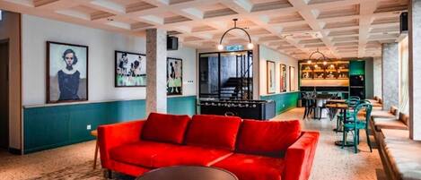 Un espace de détente moderne avec un canapé rouge, une table de billard et un coin bar doté de sièges.
