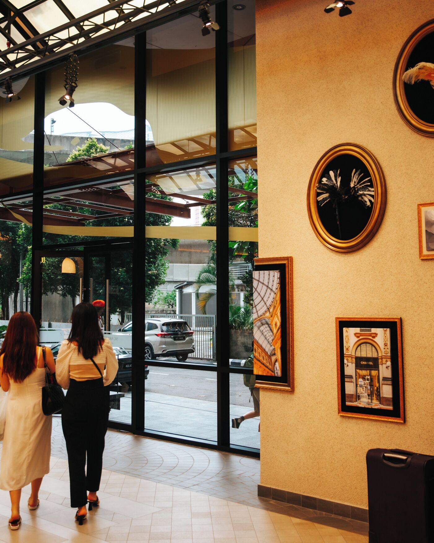 An interior with large windows, a ceiling with structural beams, and framed artwork on the walls.
