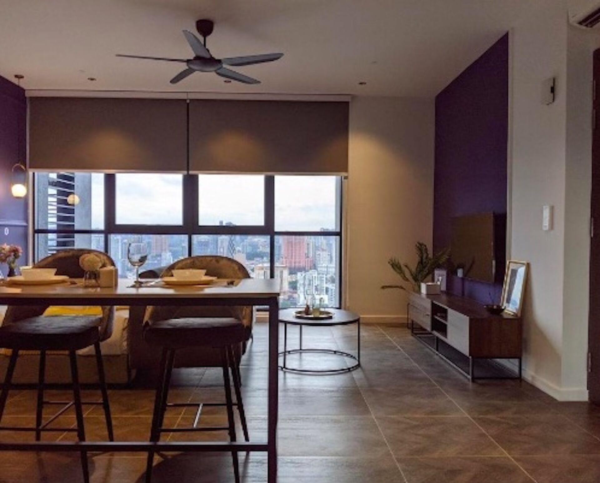 A modern dining area with a city view, a ceiling fan, and a TV on the right.