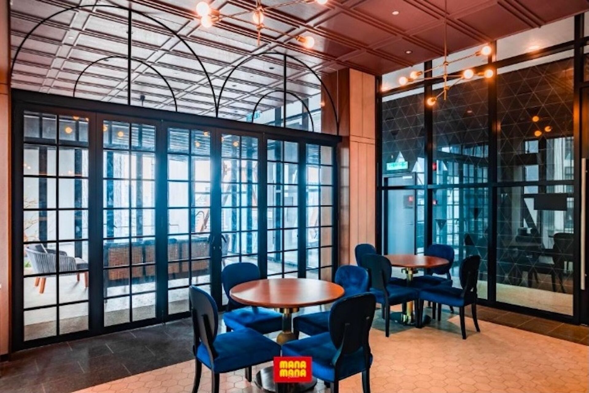 A modern interior with large windows, blue chairs, and round tables.