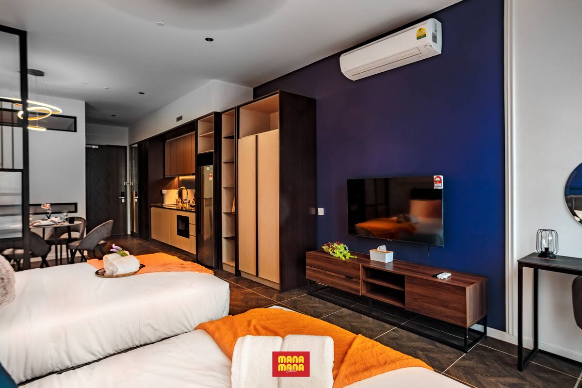 A modern hotel room with a large bed, a TV, a desk, and a wardrobe.