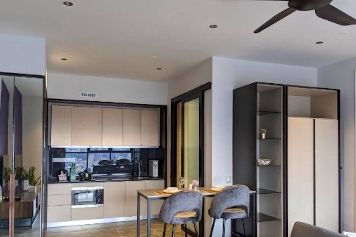 A modern kitchen with a dining area, a sofa, and a ceiling fan.