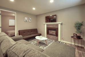 A living room with a brown sofa, a white coffee table, a fireplace, and a potted plant.