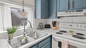 Una cocina moderna con armarios azules, un lavamanos de acero inoxidable y una estufa blanca.
