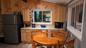 A kitchen with wooden cabinets, a refrigerator, a coffee maker, and a dining table with chairs. - Moon Lake Waterfront Getaway (Lewiston)