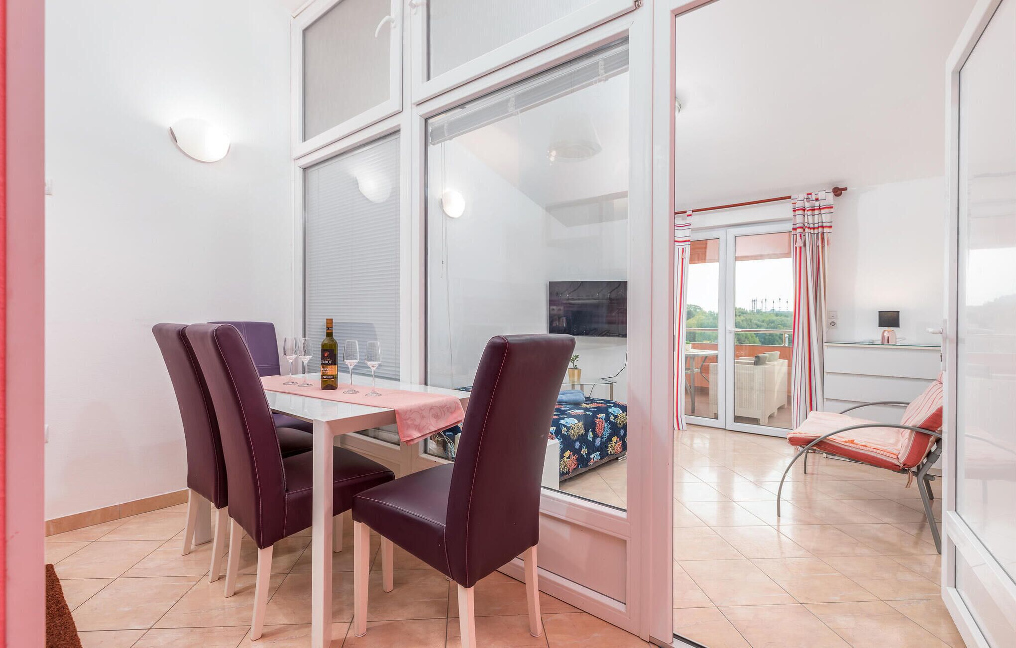 A dining area with a table, chairs, and a bottle of wine.