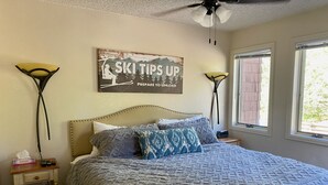 Een slaapkamer met een bed, twee nachtkastjes, een plafondventilator en een raam.