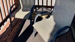 Een houten terras met twee loungestoelen van netstof en een klein tafeltje.