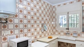 Une cuisine compacte avec des carreaux décoratifs, un four à micro-ondes, un four traditionnel et une fenêtre offrant une belle vue.