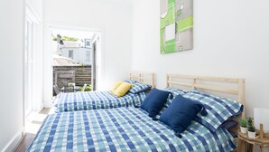 A bedroom with two beds, a wooden headboard, and a small table with a plant. - Entire 4 Bedroom Paddington Terrace (Paddington)