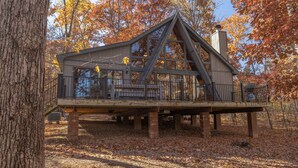 Eine Hütte mit Balkon, auf Stelzen stehend, umgeben von Bäumen mit Herbstlaub.
