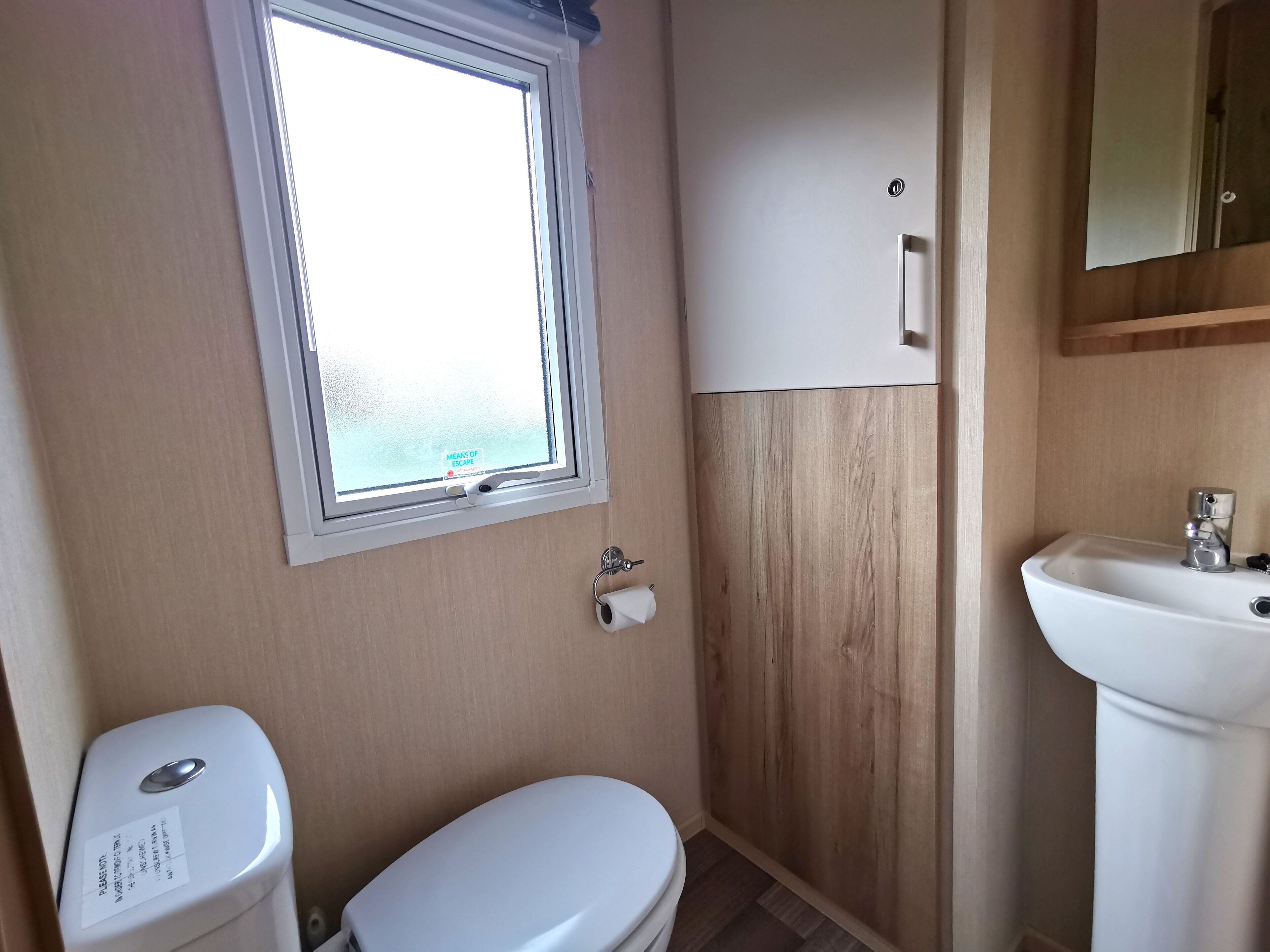 A compact bathroom with a toilet, a sink, and a window.