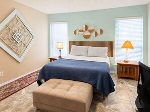 A bedroom with a bed, two bedside tables, a wall art piece, a rug, and a television. - Cheerful Home w/ Private Hot Tub, Big Fenced Yard, & Pool. Pet Friendly! (Crowley)