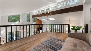Un vaste espace de vie doté d’un plancher en bois, d’un grand canapé et offrant une vue sur un balcon agrémenté d’une balustrade.