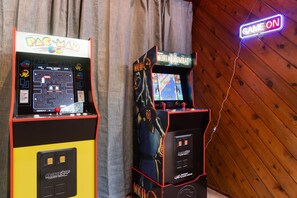 Deux bornes d’arcade, l’une portant l’inscription « Pac-Man » et l’autre « Mortal Kombat », avec un panneau néon « GAME ON » au-dessus.
