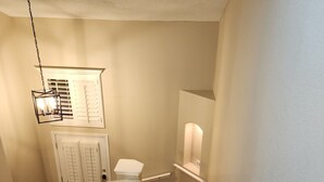 Eine Holztreppe mit weißen Geländern und einer hängenden Leuchte.