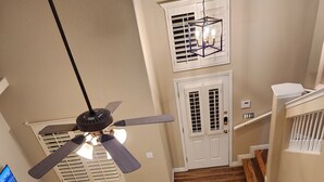 Ein Billardtisch mit Billardkugeln und Spielstangen, ein Deckenventilator und Holzdielen.