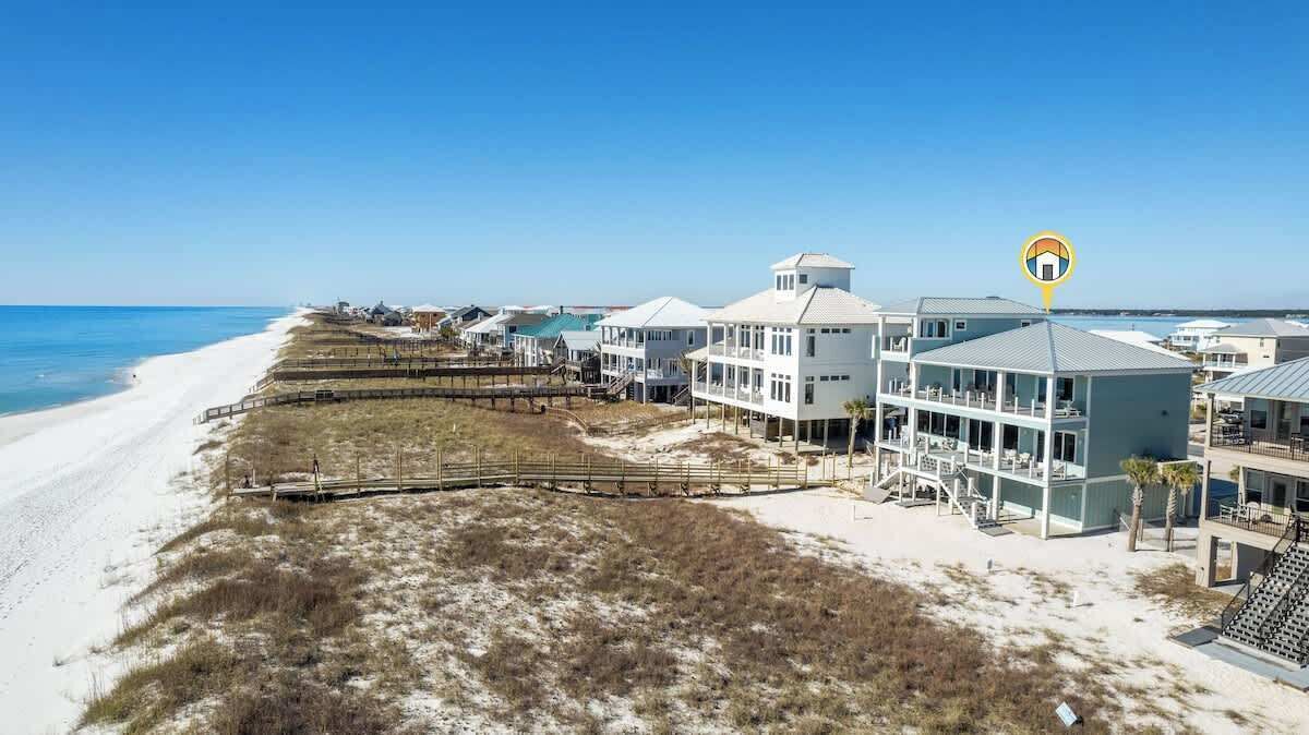 Una proprietà fronte mare con diversi edifici, una passerella in legno e una vista libera sull'oceano.